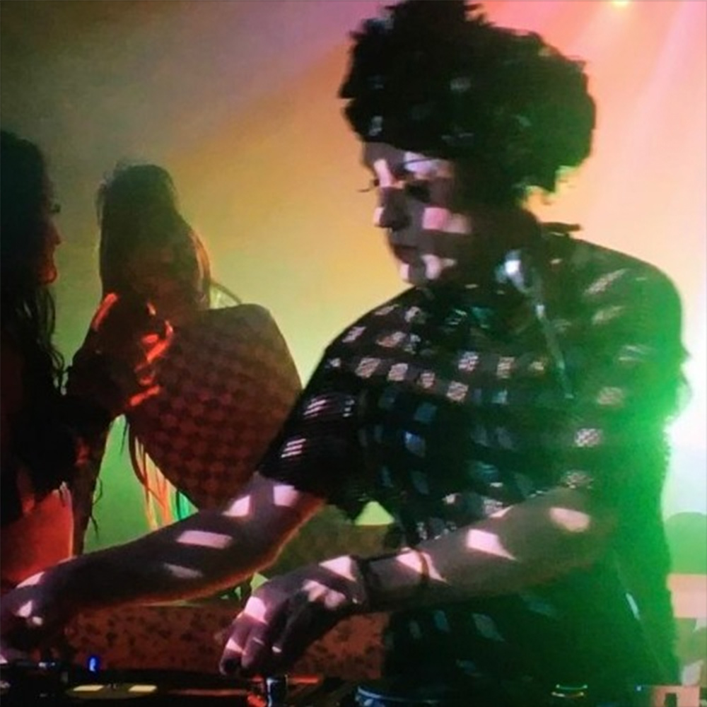 Grace Sands djs in a busy club under bright coloured lights