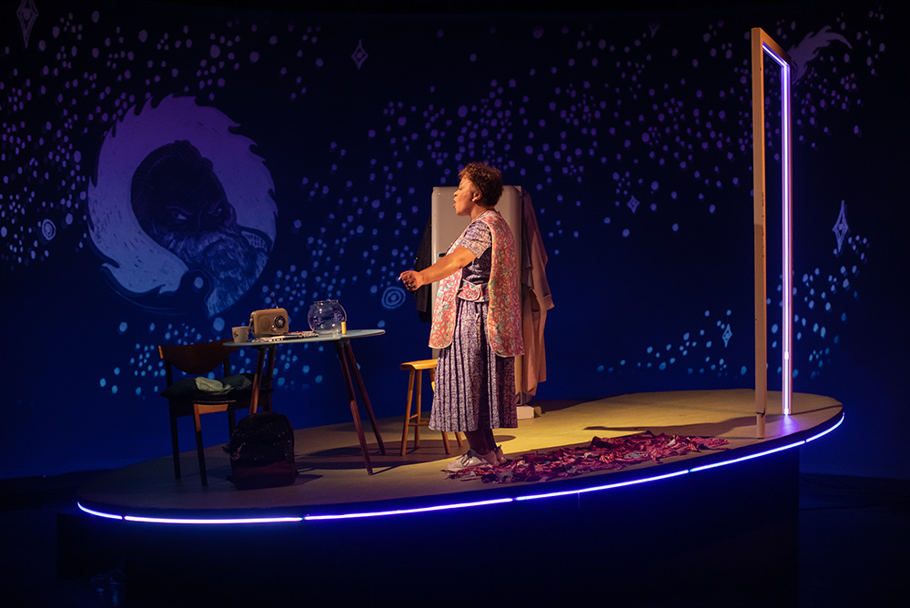 MRS dances on the stage, lit by neon blue, with a portal-like doorway. An animated starry galaxy moves in the dark blue backdrop