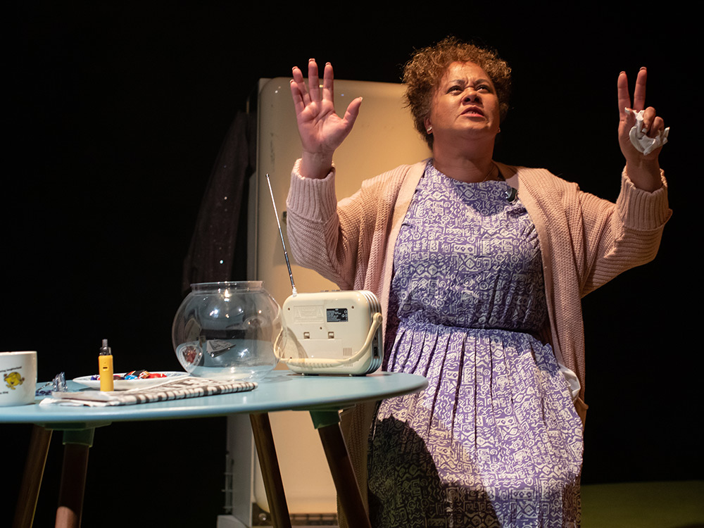 MRS sits at the table with her hands held high, gesturing at the night sky