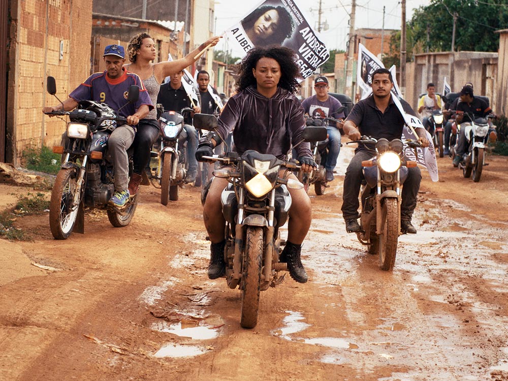 Brown woman on motorbike leading a pack of riders in protest