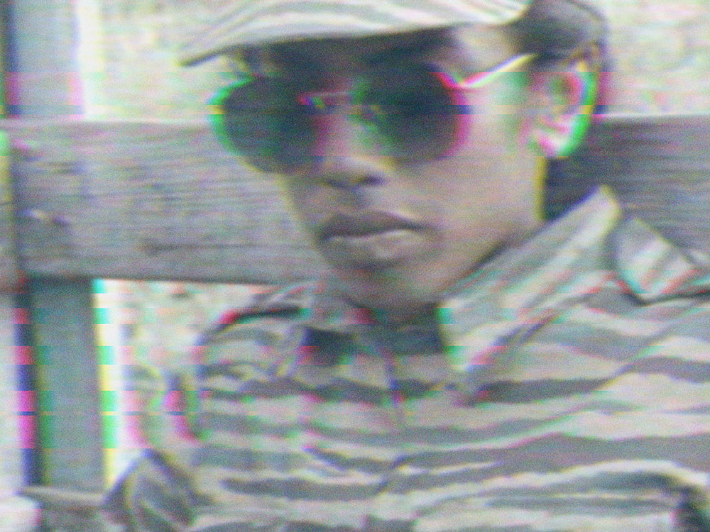 Distorted RGB-tinted image of a young person wearing sunglasses in military uniform