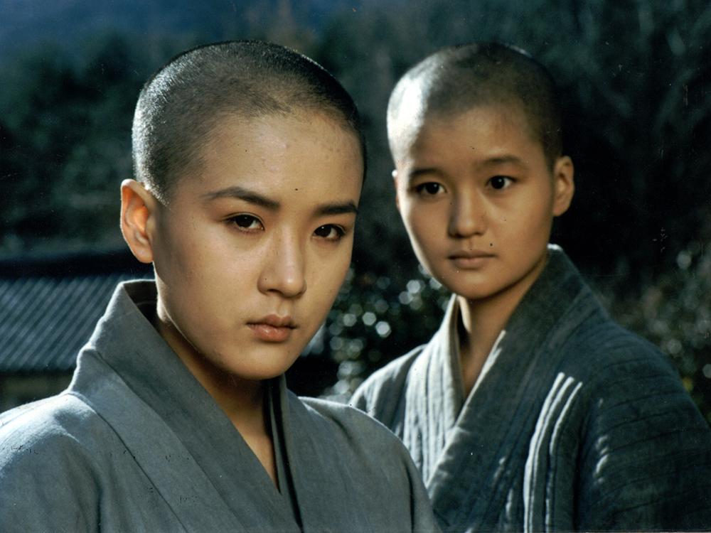 Two Korean Buddhists in robes look towards the camera deep in thought/observation