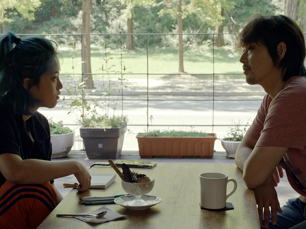 A Korean Man and Women sit over coffee and desert in a quiet cafe