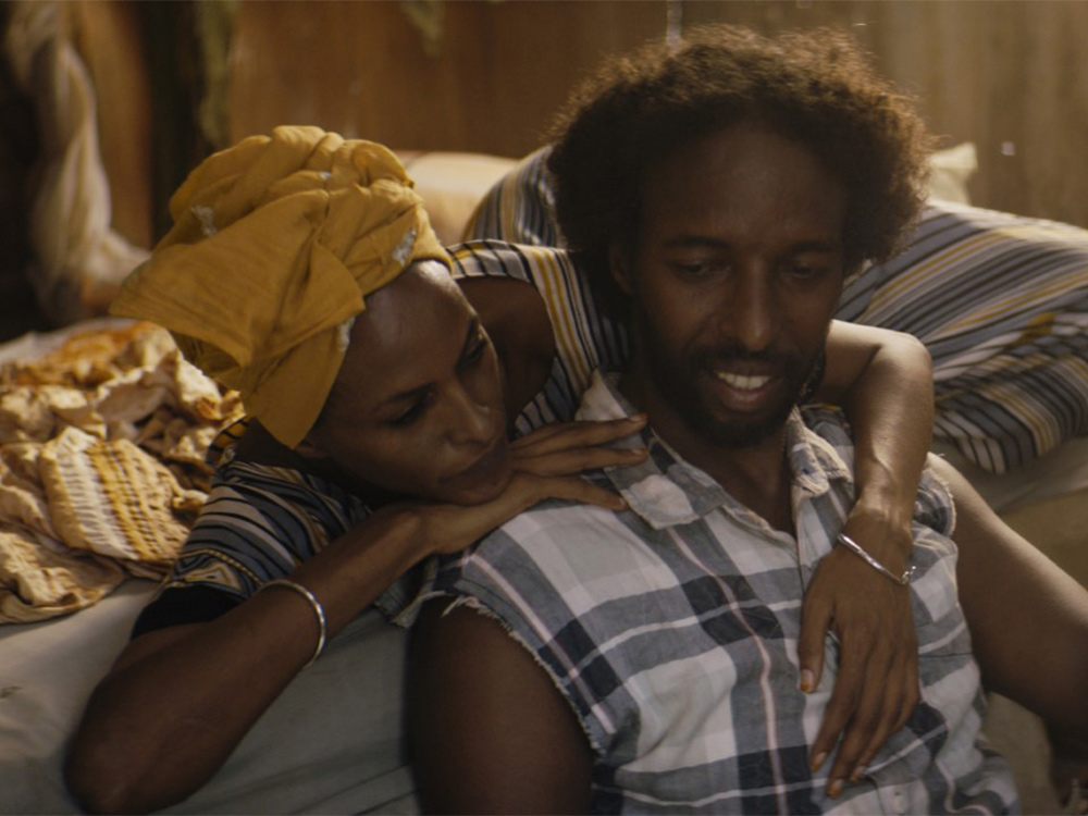 A couple sit on a sofa, embracing and enjoying their time