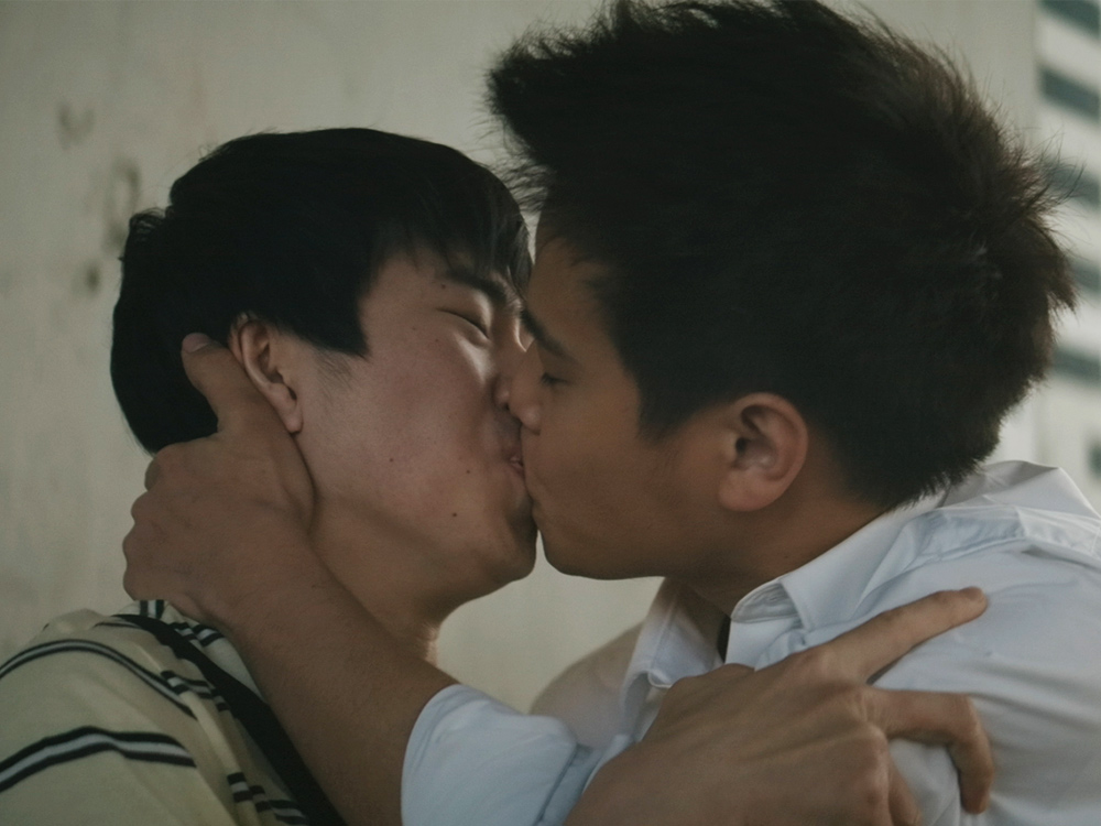 A Japanese and mixed race Filipino boy embrace in a strong kiss