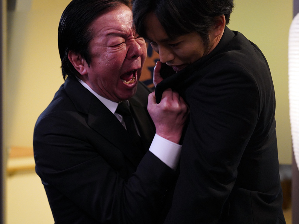 An angry Japanese salaryman screams with fury in someone's face, grabbing them by the jacket
