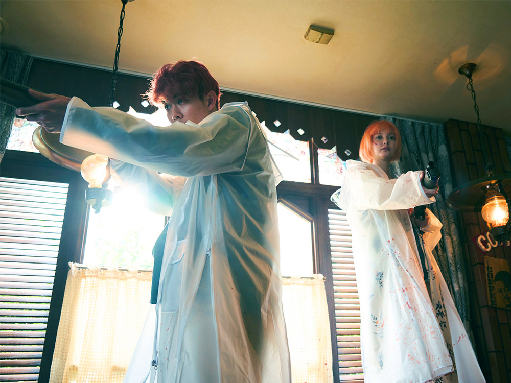 A couple with bright hair and white coats stand off in a love hotel, aiming shotguns
