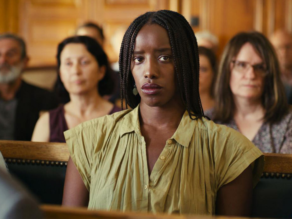 A young mother sits in a court room alone, her expression neutral