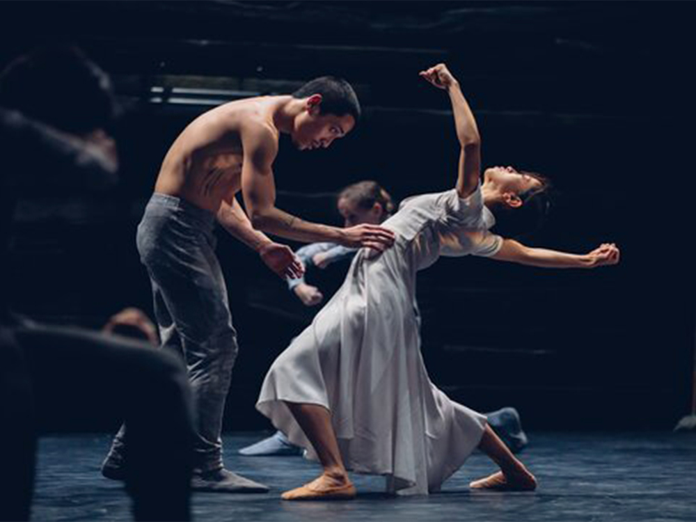 Two dancers rehearse with wide, expressive gestures