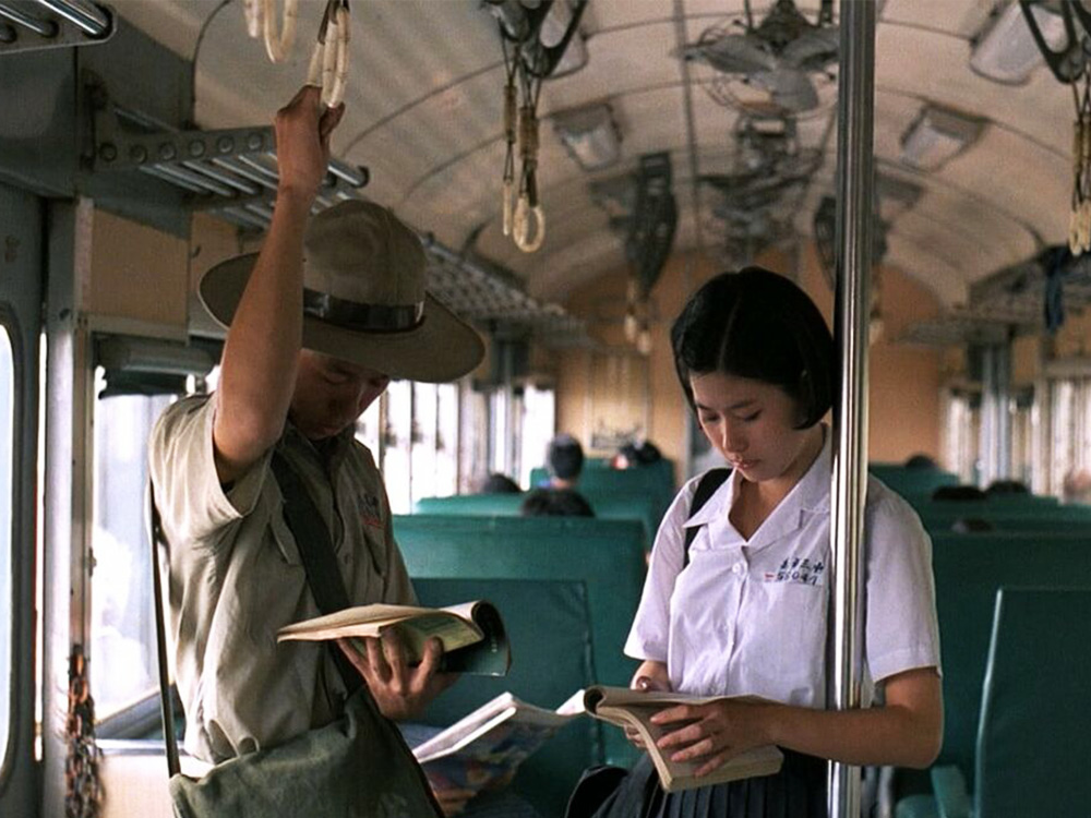 A young Taiwanese couple, dressed in military unform and school uniform, read books on a train into the countryside