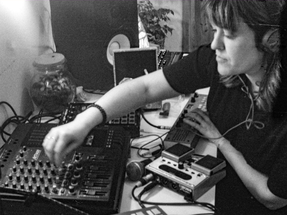Musician Elaine Howley plays with a mixer, MIDI controllers and effects pedals on a home studio table