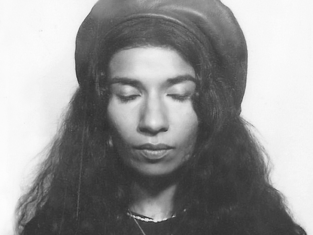 Nabihah Iqbal stares at the camera, eyes closed. She has long hair and is wearing a flat cap.