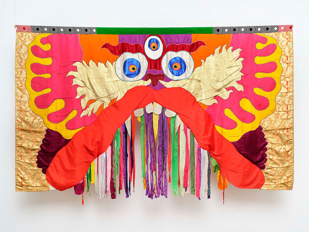 A colourful dragon in tapestry, with colourful streamers hanging from its mouth