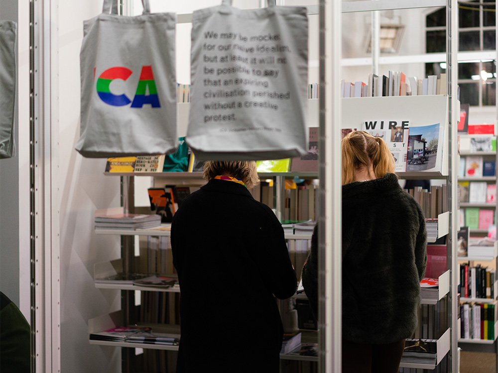 Two people staring at a rack of magazines in the ICA Bookstore