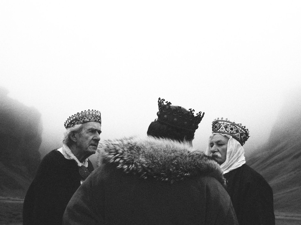 Three kings consult in the middle of a black and white foggy desert