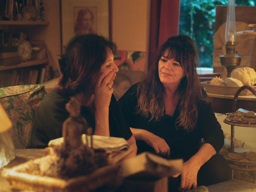 Two women have a quiet conversation on the couch at home