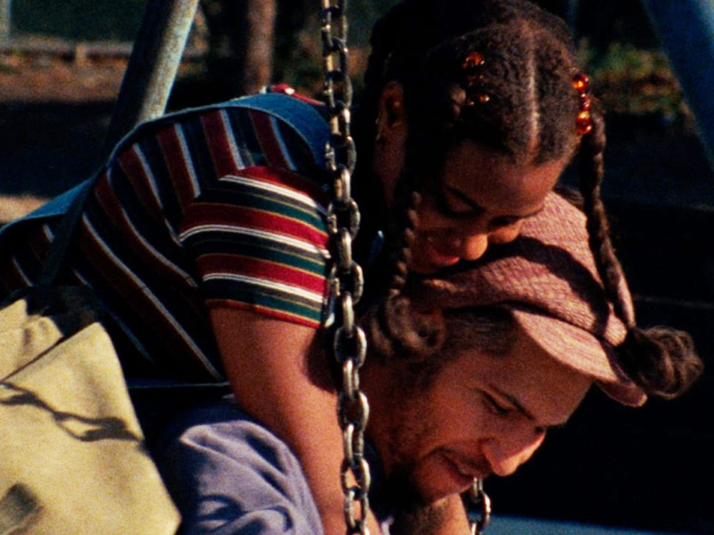 A daughter rests on a man's back, on a swing