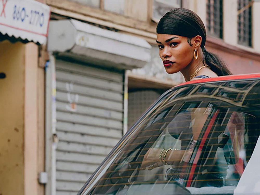 A young black mother stands outside her car in a neighbourhood street of New York city