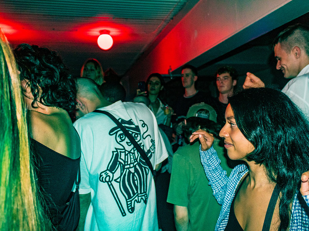 A group of people dance under a red light in the ICA Upper Bar