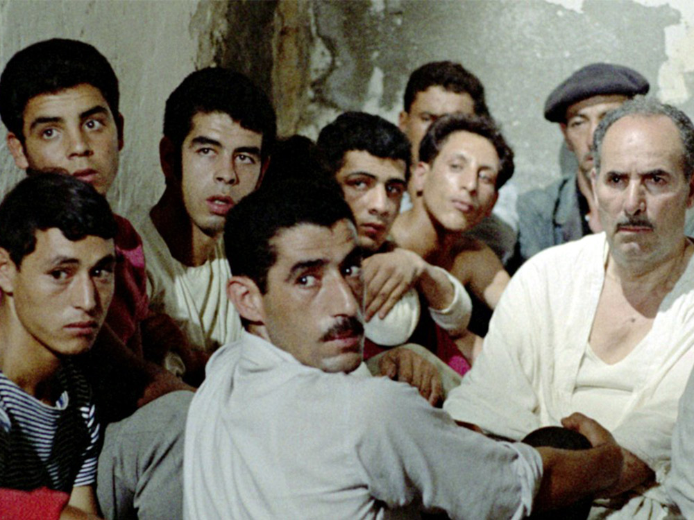 A group of Algerian men in a concrete room stare