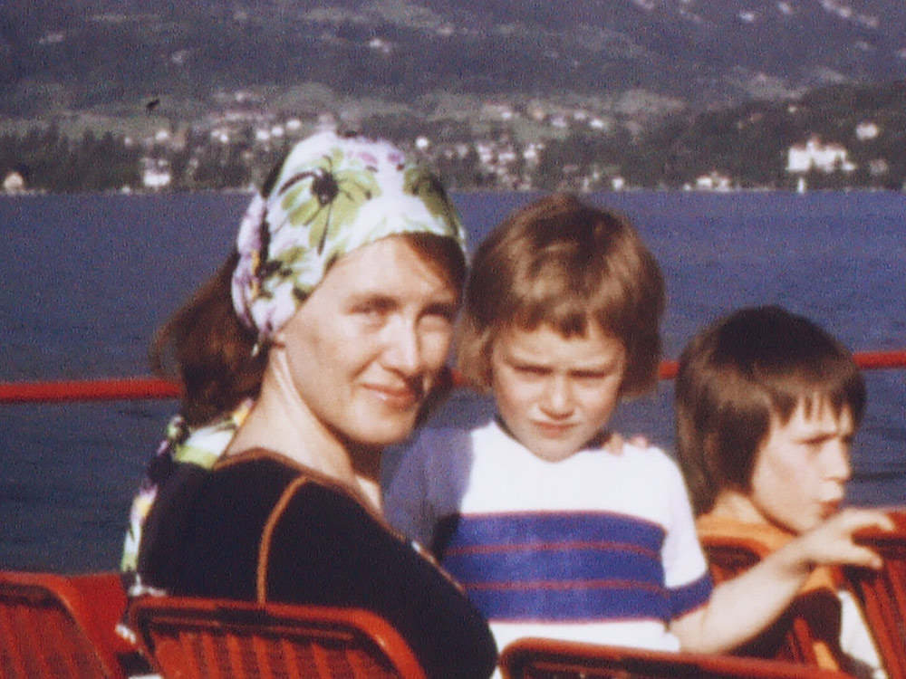 On super 8 film, Annie Ernaux sits in a boat on a lake with two children