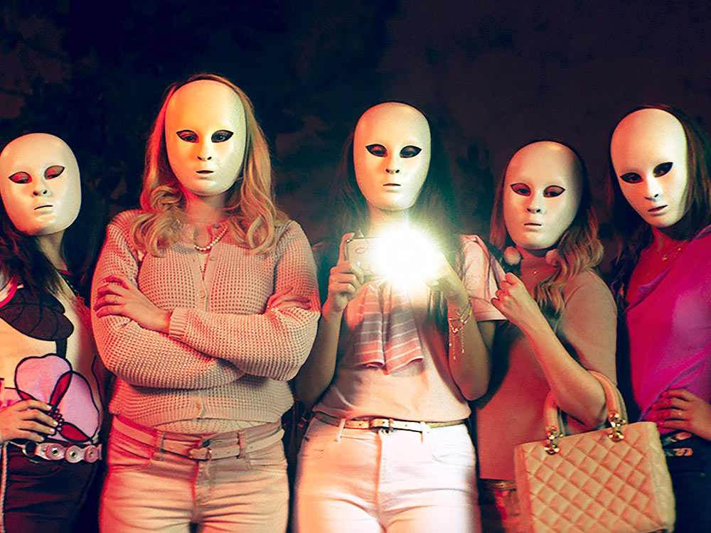 A gang of expensively dressed women wear white masks and take a photo