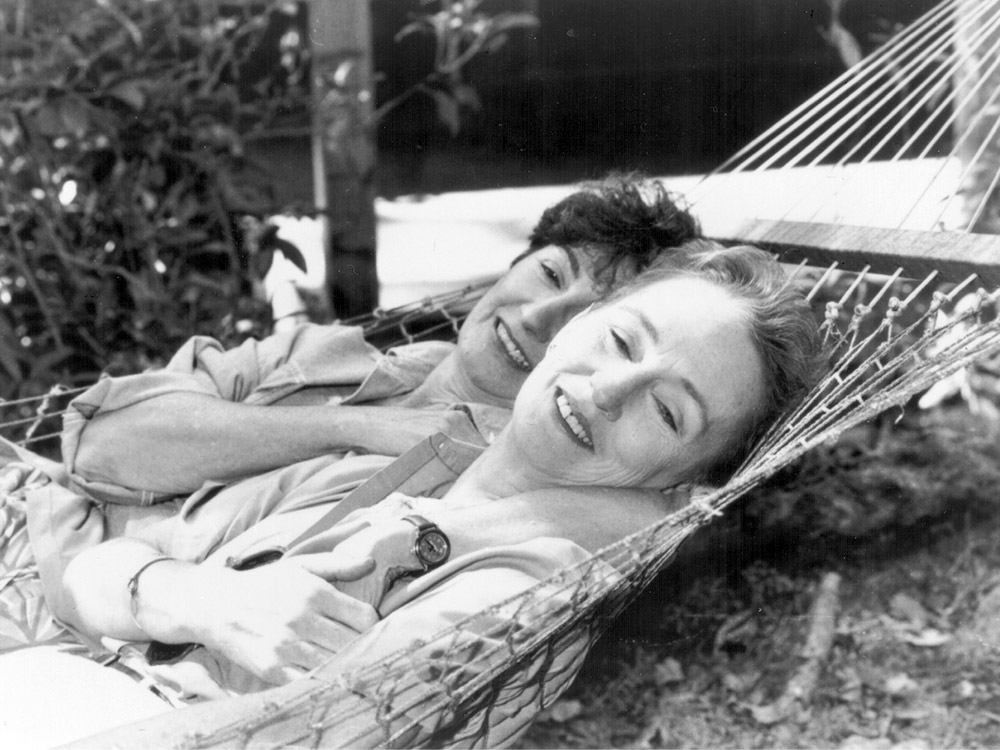 Two women lying in a hammock together, smiling