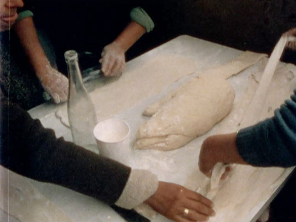 A group of hands prepare a large mound of dough into strips