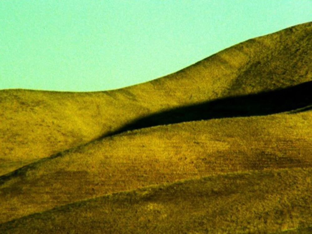 A brown hill against a teal sky