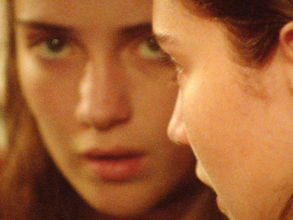 Close ups of two white women's faces, right next to one another, almost touching