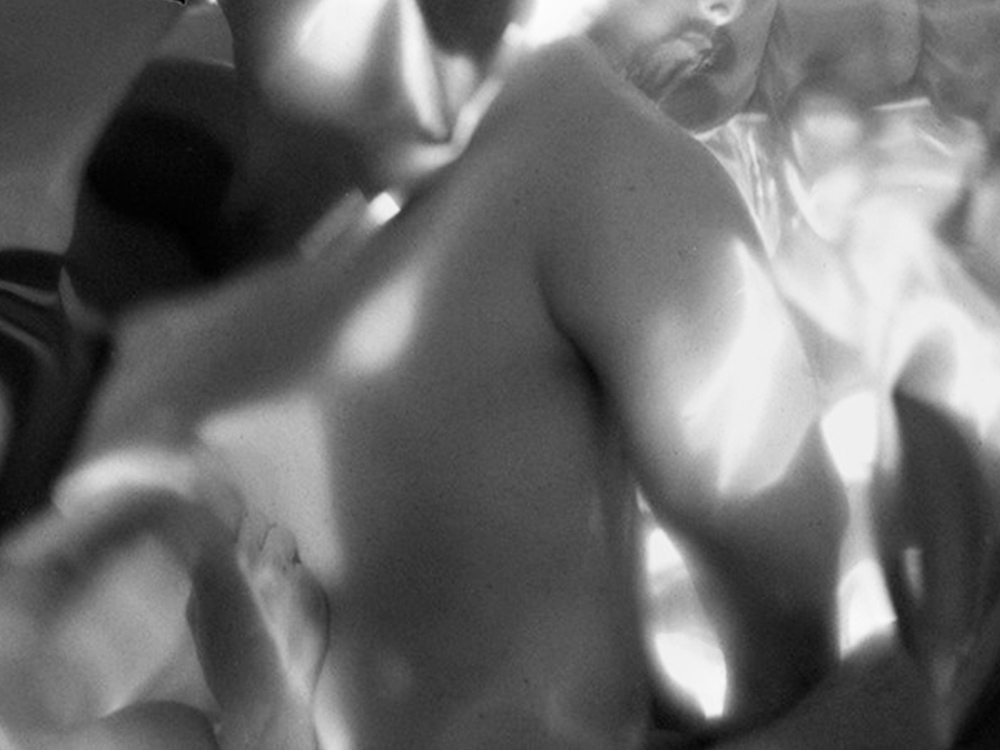 A close-up of bodies against one another, light and shadows reflecting off their skin