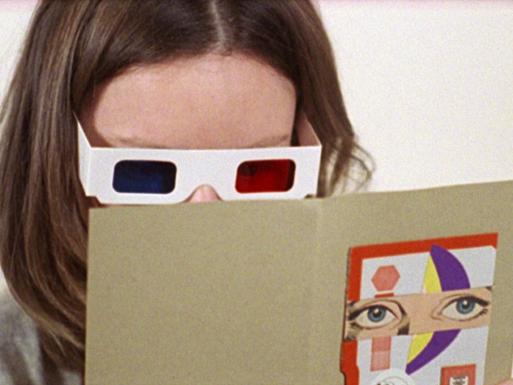 A young person reads a card with 3D glasses on