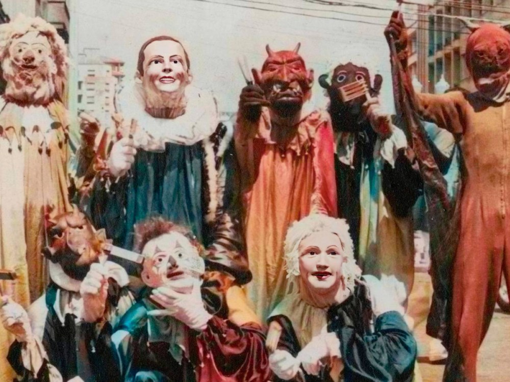 A group of people dressed up for Carnival in Recife, with costumes of human masks and red-faced spirits