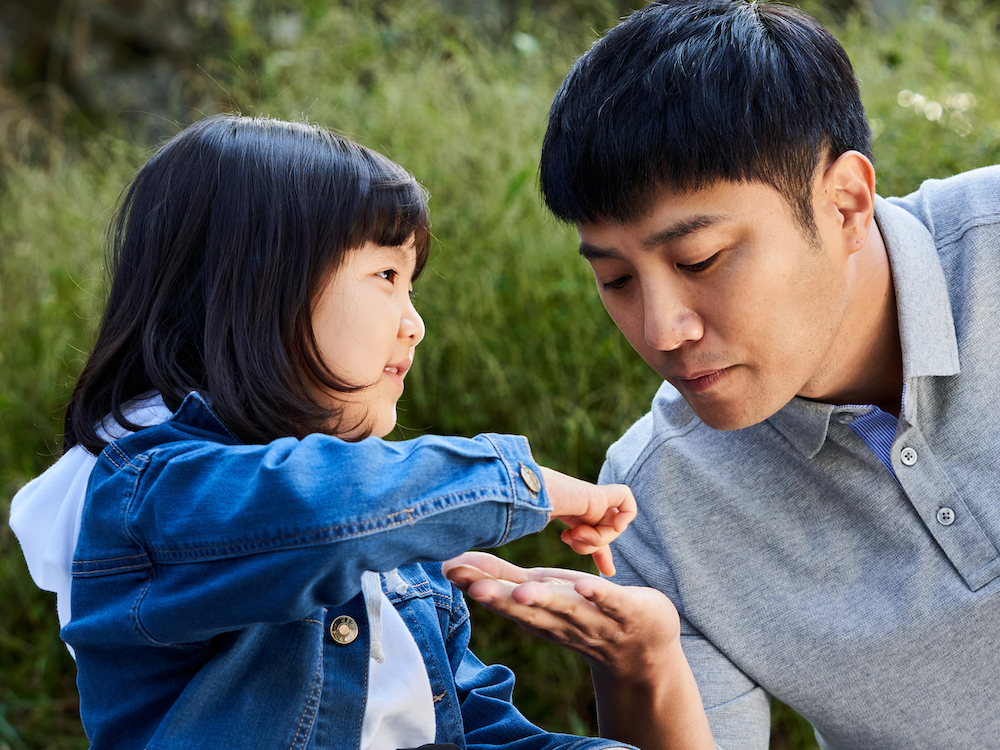 A young girl playfully places the tip of her finger into a man's palm
