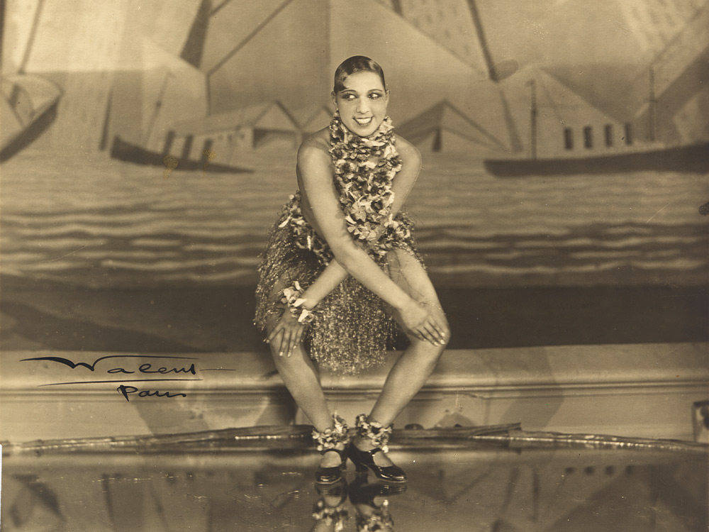 A sepia photo of Josephine baker dressed up for a performance on a stage