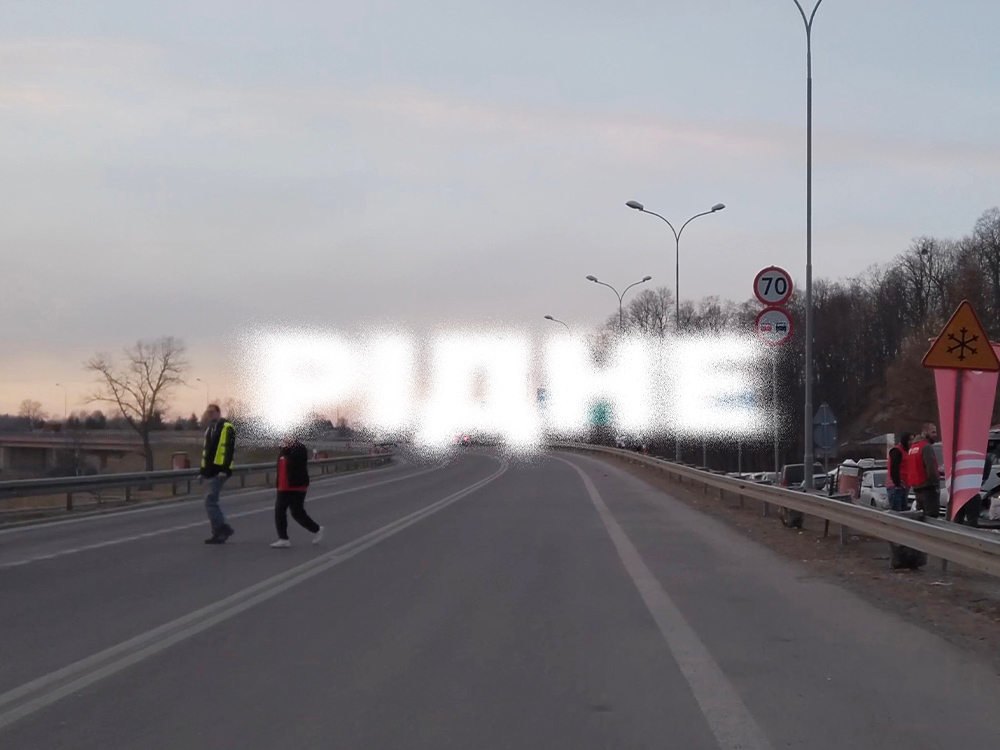 Russian word 'RIDNE' over a highway at sunset