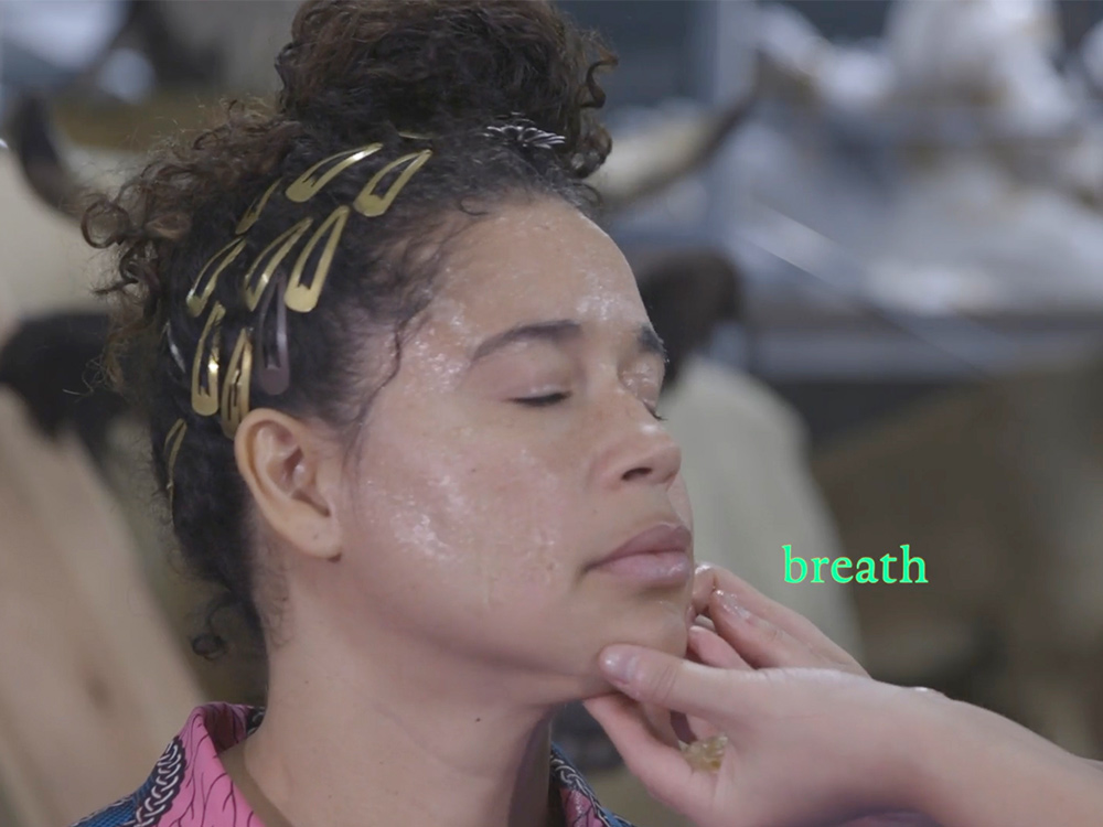 A person touches a black woman's chin. The woman's eyes are closed. In small green text: 'breath'