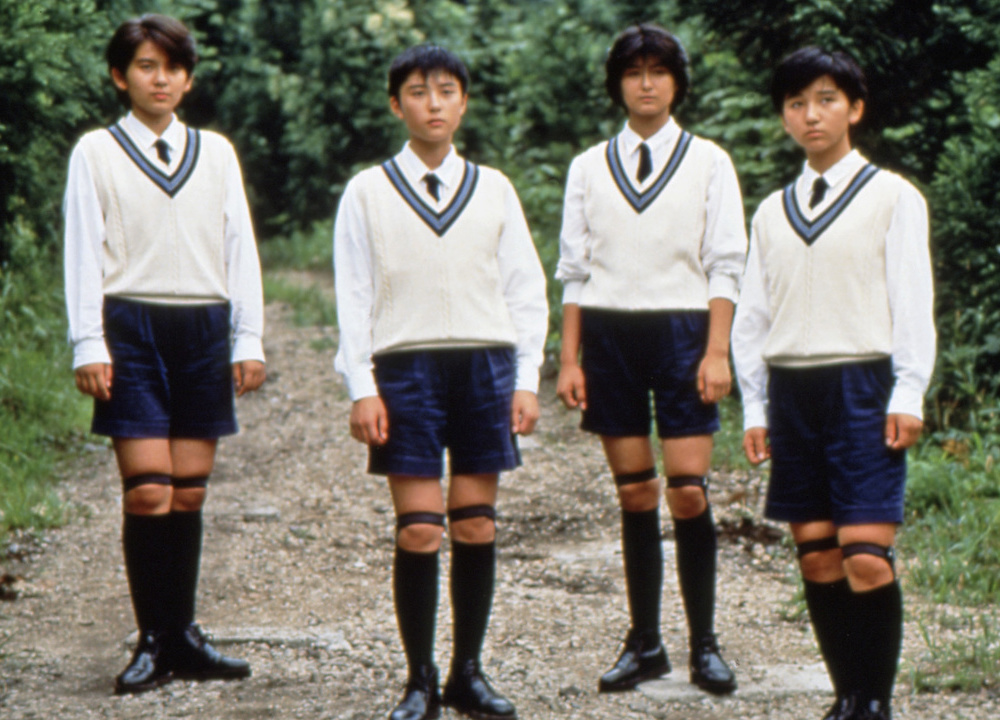 Four Japanese school boys stand in a forest path