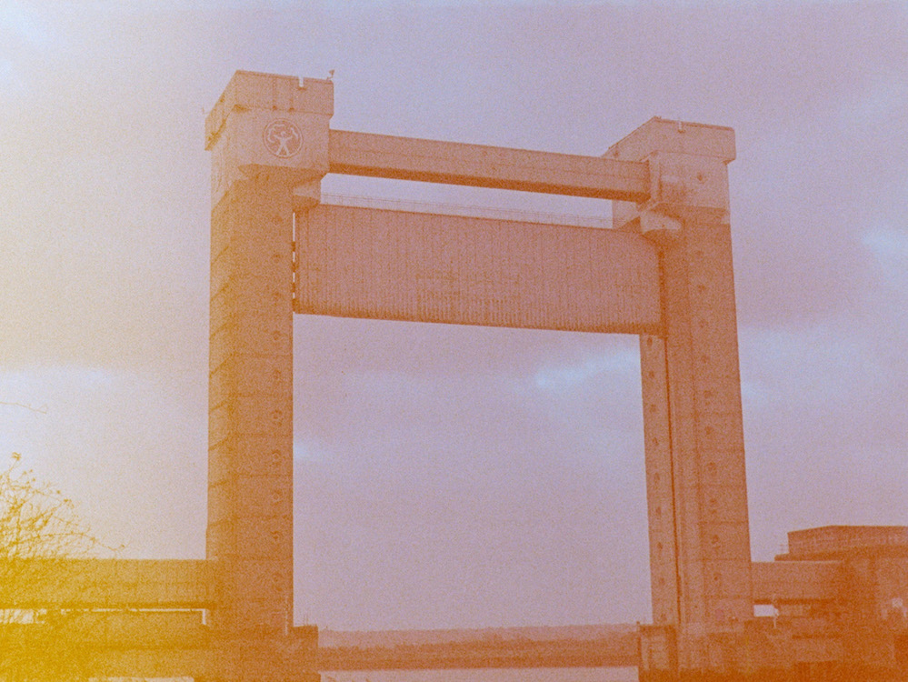 A tall flood barrier against a cloudy sky, in a washed out colourful photo