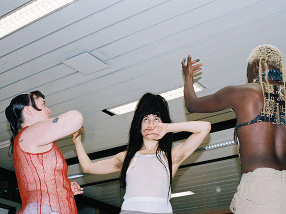 Two white people and a black person moving their arms in a choreographic way